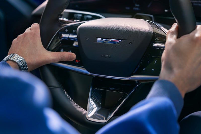 Close-up of a Man About to Press the V-Button on the 2026 OPTIQ-V Steering Wheel | Orr Cadillac Fort Smith in Fort Smith AR